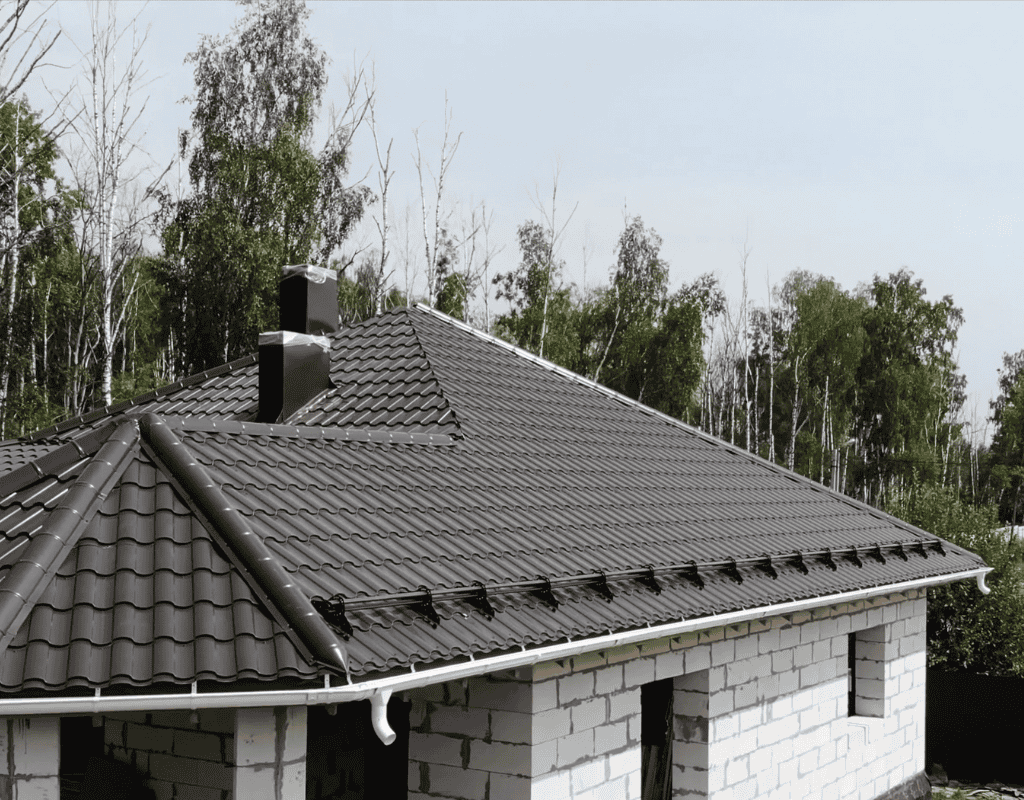 Newly installed residential roof with metal tiles on home surrounded by trees