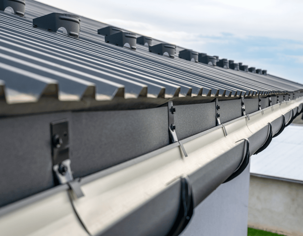 Close up of modern metal gutter system installed along standing seam roof