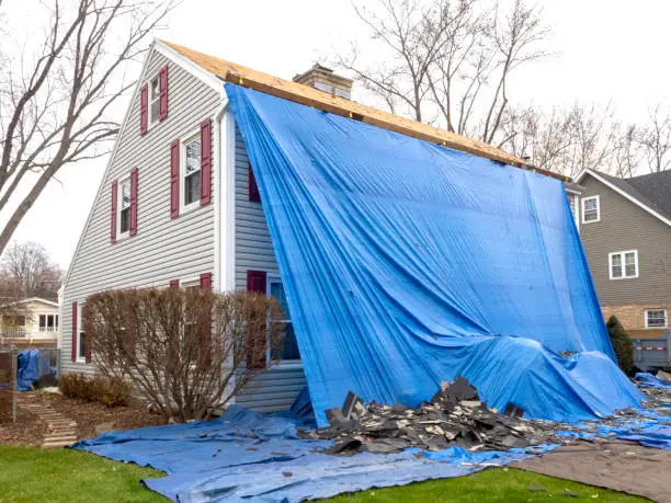 Roof repair crew tarping active leak on Chicago home after severe storm